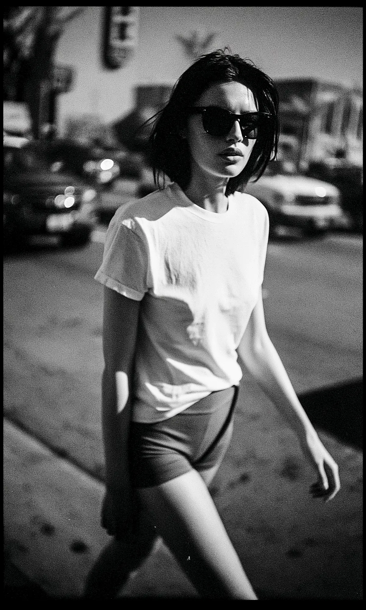 Street candid of a model in white tee and shorts, infrared film grain